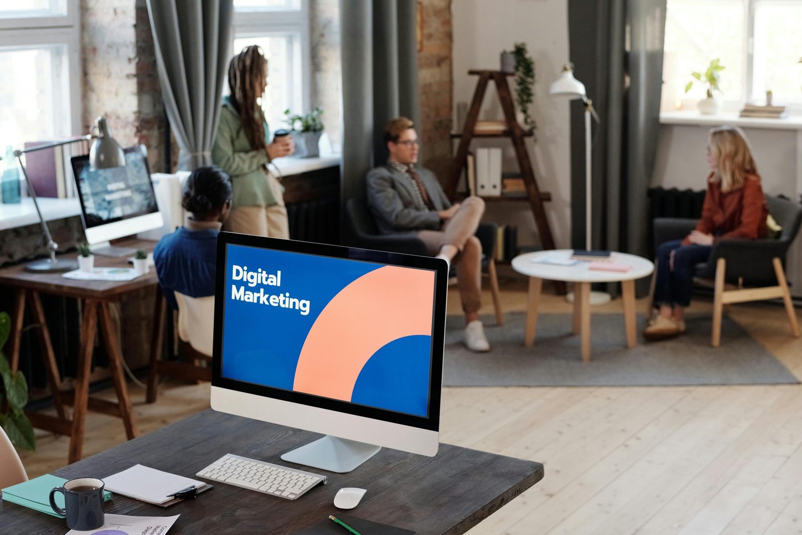 People Having a Meeting Behind a Computer Screen that says Digital Marketing